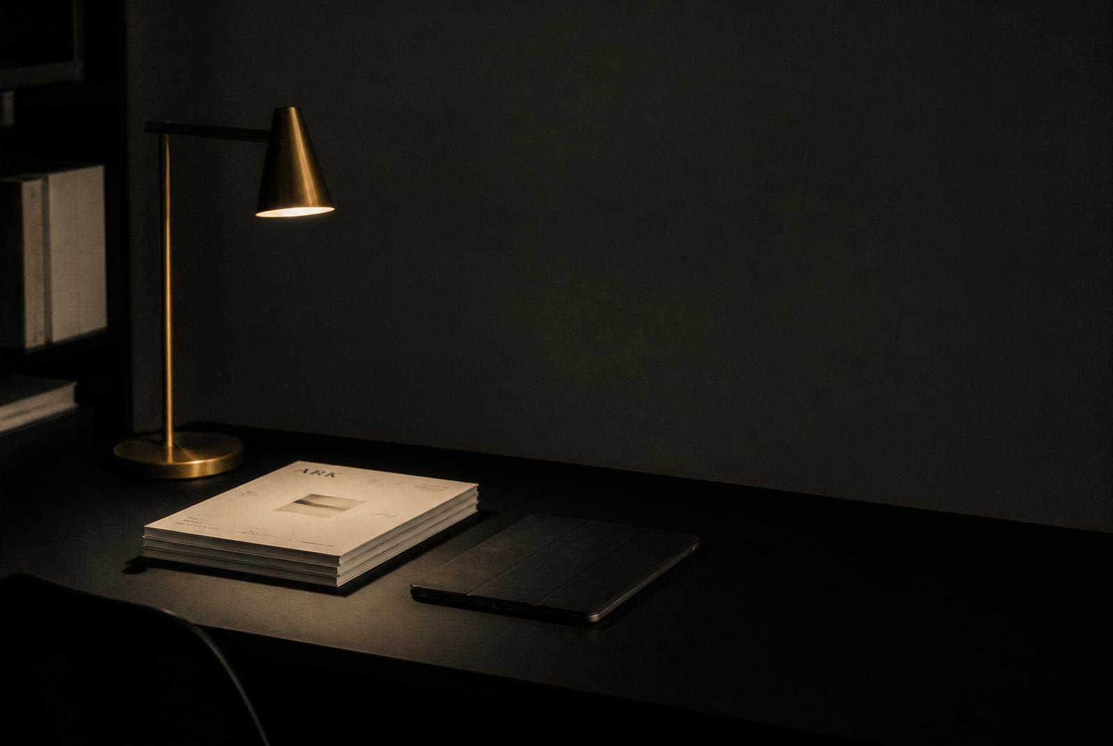 A quiet desk lit by warm brass light — considered clinical review